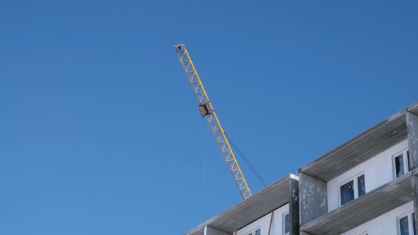 Construção de um edifício de vários andares. Guindaste vira para o lado sobre o telhado . — Vídeo de Stock