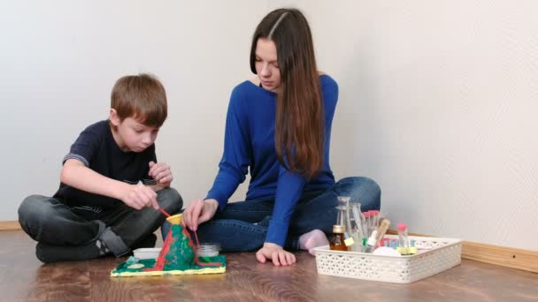 Niño de 7 años y su madre hacen la experiencia con el volcán. Reacción con la liberación de gas . — Vídeos de Stock