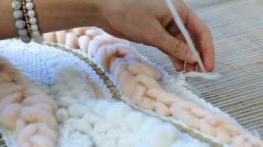 Tezgâh üzerinde dokuma. Kadının eller iplik dokuma tezgâhı konu ile çalışır. Yan görünüm.