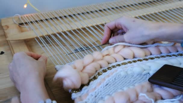 Tissage sur un métier à tisser. Gros plan sur un métier à tisser. Enfiler l'aiguille à travers les brins du cadre et attacher le fil avec des pétoncles, peigne . — Video