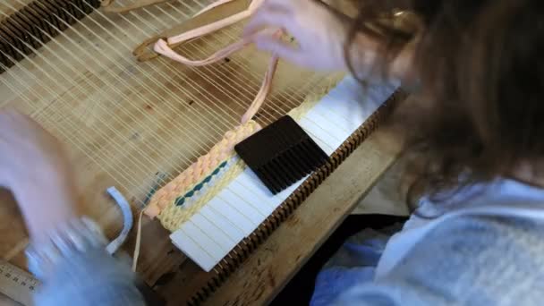 Closeup womans hands weaving on a loom frame and fasten the yarn with scallop. — Stock Video