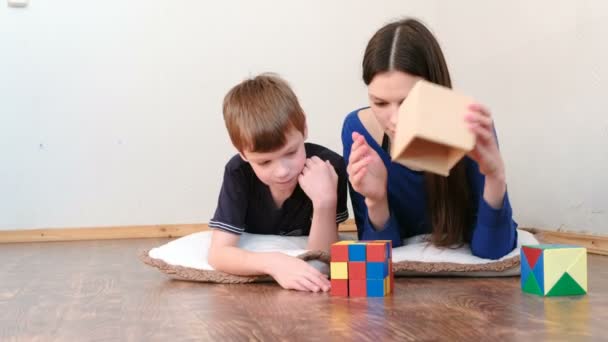 Madre e figlio giocando blocchi di giocattoli educativi colorati in legno sdraiati sul pavimento . — Video Stock