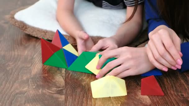 Closeup mom and sons hands are building from plastic constructor with non-ferrous magnetic triangles lying on the floor. — Stock Video