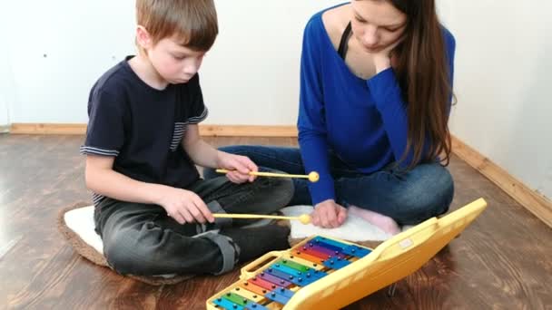 Tocando instrumento musical. Mamá y su hijo jugando xilófono sentado en una habitación en el suelo . — Vídeos de Stock