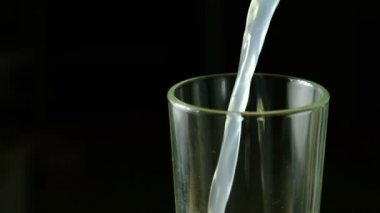 Gazlı soda içecek sarı bir cam içine siyah bir arka plan üzerine dökülür. Closeup cam yarısı.