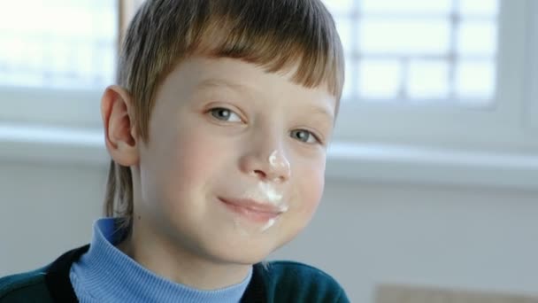 Grimy smiling seven year old boy licking the ice cream standing at the window. — Stock Video