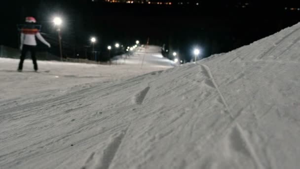 Az ember megy le a hegyről egy snowboard lejtőn, a felvonó mellett. Este snowboard. — Stock videók