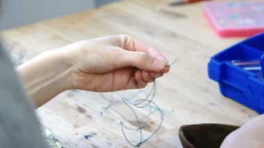 Boncuk takı yapım Atölyesi iş parçacığı üzerinde çekimi bir kadının el Close-Up.