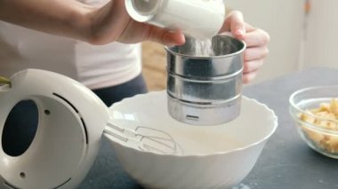 Yakın çekim kadının elleri un bir elekten elemek ve bir karıştırıcı ile hamur yoğurmak. Yemek elma pasta.