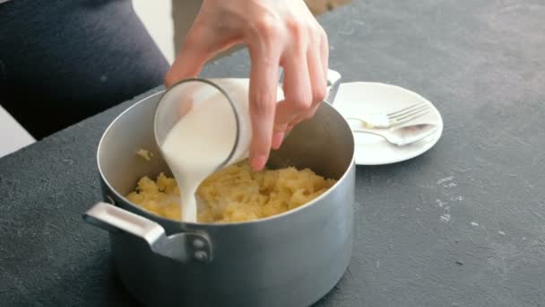 Fechar as mulheres mão fazendo purê de batata, adicionando leite e misturá-lo com misturador em panela. Cozinhar purê de batatas . — Vídeo de Stock
