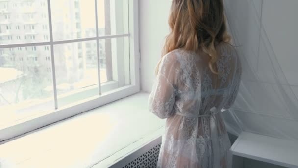 Jeune fille blonde sexy mince en lingerie et boudoir debout près du rebord de la fenêtre et primp. Vue arrière . — Video