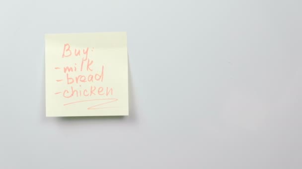 Nota en hojas de papel adhesivo amarillo palabras comprar: leche, pan, pollo en la pizarra blanca. Nota de familia . — Vídeos de Stock