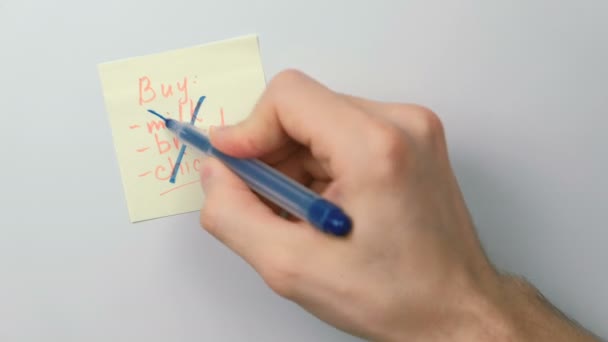 Closeup mans hands write on yellow sticker paper sheets word beer instead shopping list. — Stock Video