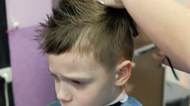 Barbers руки гребінці та різання блондин короткий хлопчиків волосся ножицями. Крупним планом обличчя хлопчиків. — стокове відео