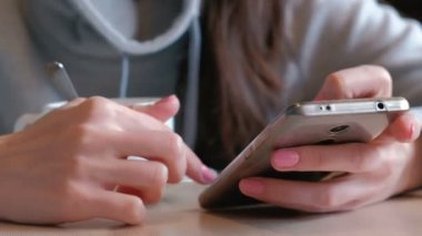 Kadın sıcak çikolata kaşık ve göz ile cep telefonu kafede oturan ekranda içiyor. Kadının eller.