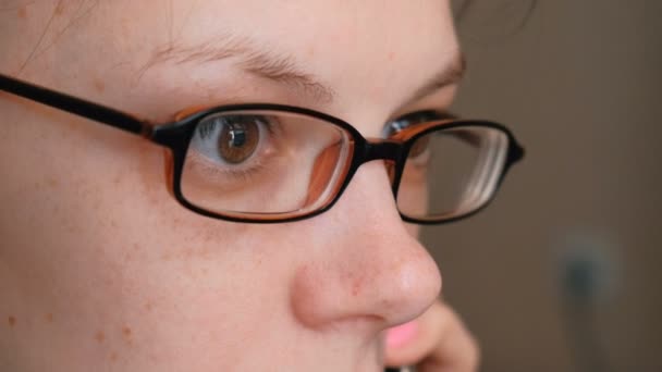 Mujer en gafas está hablando de teléfono móvil y mirando hacia el futuro. Primer plano de los ojos — Vídeo de stock