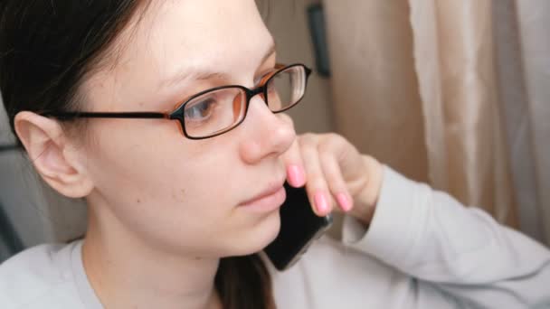 Frau mit Brille spricht Handy und blickt voraus. Seitenansicht. — Stockvideo