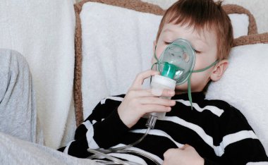 Nebulizatör ve astım tedavisi için kullanma. Kanepede yatan inhaler maskesi aracılığıyla teneffüs edilmesi cloused gözlü çocuk.