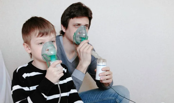 Use nebulizador e inalador para o tratamento. Homem e menino inalando através da máscara do inalador. Vista lateral . — Fotografia de Stock