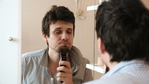 Máquina afeitarse el pelo facial. Joven hombre somnoliento afeitado en seco con trimmer eléctrico . — Vídeos de Stock