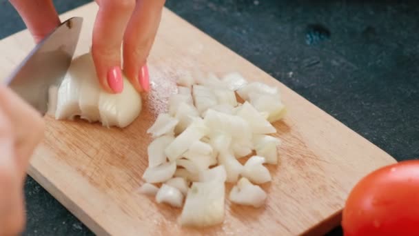 Primeros planos de las manos de las mujeres cortando una cebolla en una tabla de madera . — Vídeos de Stock