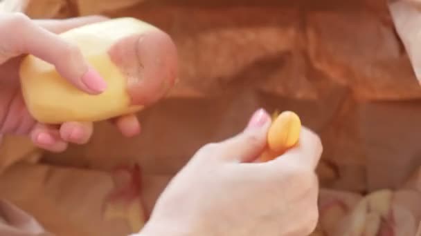 Κοντινό πλάνο γυναικεία χέρια ξεφλούδισμα πατατών. — Αρχείο Βίντεο
