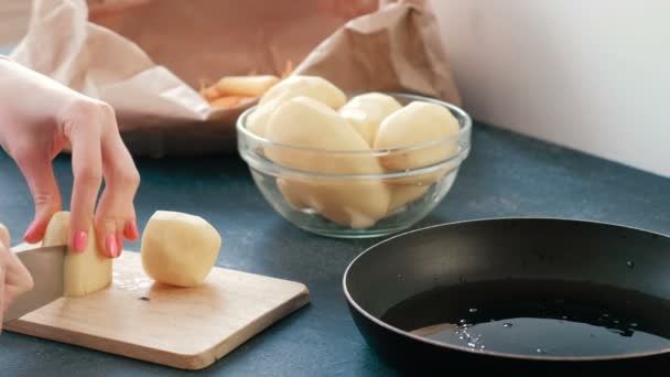 Close-up vrouwen handen snijden van een aardappel op een houten plank. — Stockvideo