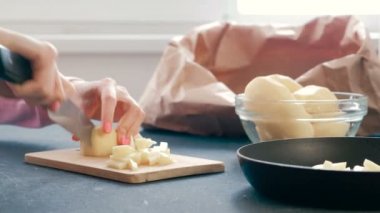 Closeup womans ahşap bir gemide bir patates kesme eller ve yağ ile bir tavada koydu.