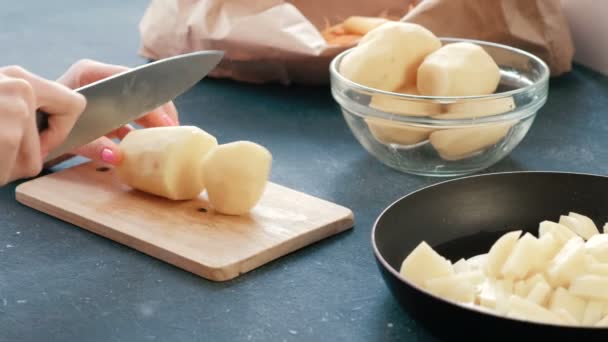 Primeros planos de las mujeres manos cortando una patata en una tabla de madera . — Vídeos de Stock