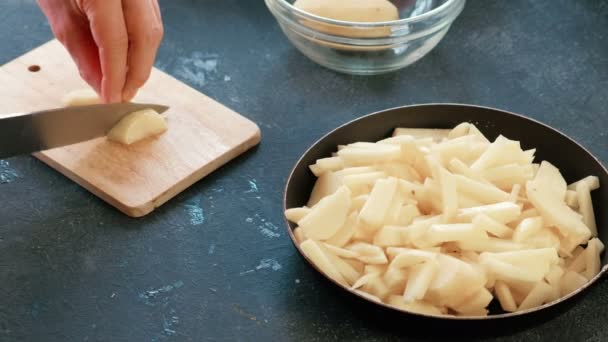 Mãos de homem de close-up que cortam uma batata em uma tábua de madeira e o põem em uma panela de ato de fritar com o óleo . — Vídeo de Stock