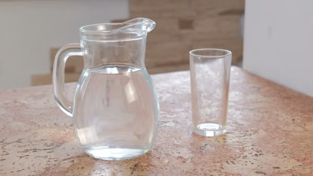 Dekanter mit Wasser und einem leeren Glas auf dem Tisch. — Stockvideo