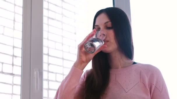 Молодая женщина пьет воду из стекла . — стоковое видео