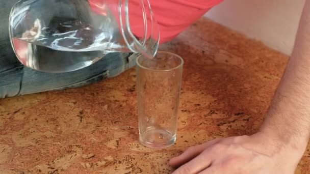 Closeup mans hand een karaf water naar glas gieten en neemt een glas. — Stockvideo