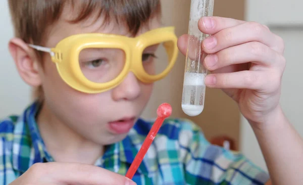 室内化学实验。特写男孩的脸。化学反应与释放气体在试管中的一个惊讶的男孩手中. — 图库照片