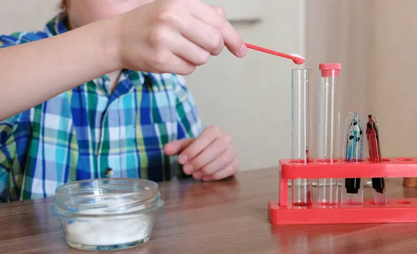 Expériences en chimie à la maison. Garçon effectue une réaction chimique dans une éprouvette . — Photo