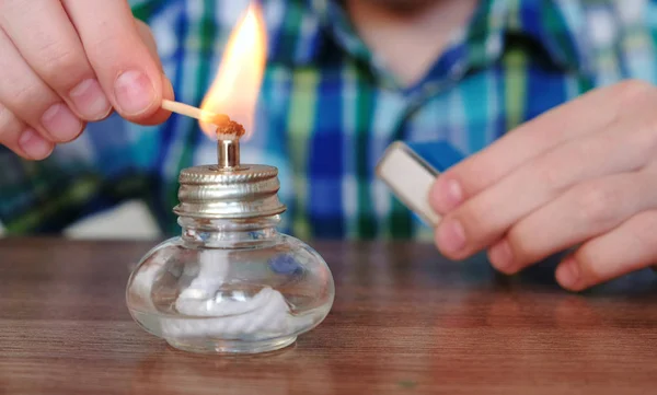 Experiências de química em casa. Closeup Boys mãos define a lâmpada de álcool em chamas no fogo com um fósforo . — Fotografia de Stock