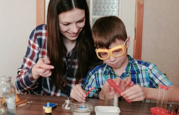 Experimentos de química en casa. Mamá e hijo hacen una reacción química con la liberación de gas en el tubo de ensayo . —  Fotos de Stock