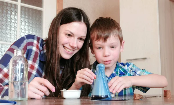 Experimentos de química en casa. Sorprendidos mamá e hijo hacen una reacción química con la liberación de gas en el frasco . — Foto de Stock