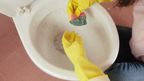 Primeros planos de las manos de las mujeres en guantes de goma amarilla lavar el inodoro con esponja. Vista superior . — Vídeos de Stock