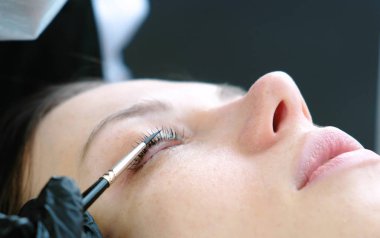 Güzellik uzmanı fırça ile istemciler kirpik losyonları. Botox ve kirpik laminasyon. Tatlı gözler.