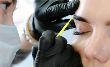 Güzellik uzmanı ile bir pamuklu çubukla womans kaşları losyonları. Düzeltme kaş. Closeup Önden Görünüm.