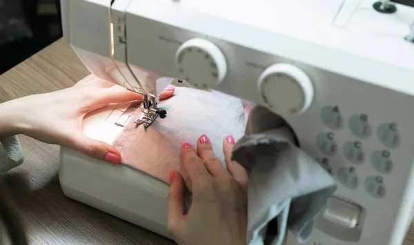 Женщина пришивает светлую ткань к швейной машинке крупным планом. Вид сбоку . — стоковое фото