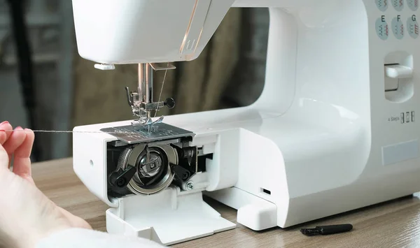 Close-up mãos femininas testar máquina de costura após o reparo, puxando o fio. Vista frontal . — Fotografia de Stock