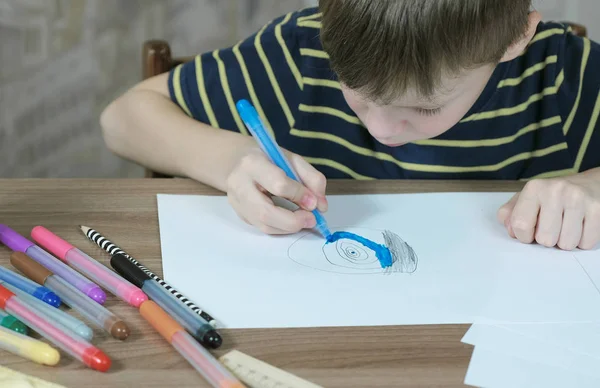 Ragazzo di 7 anni dipingere il quadro con un pennarello blu su carta bianca . — Foto Stock