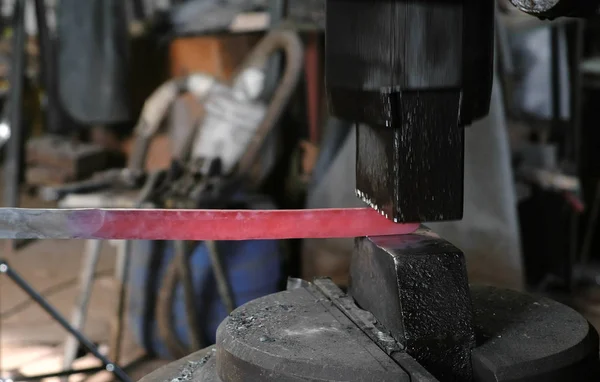 Using pneumatic hammer to shape hot metal. Making the sword out of metal. Side view. — Stock Photo, Image