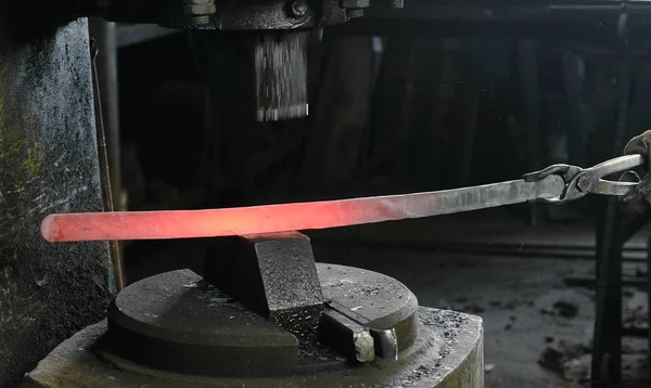 Mit Presslufthammer heißes Metall formen. macht das Schwert aus Metall. Seitenansicht. — Stockfoto