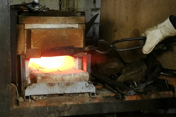 A fazer a faca de metal na forja. Aquecimento de tarugos de metal no forno . — Fotografia de Stock