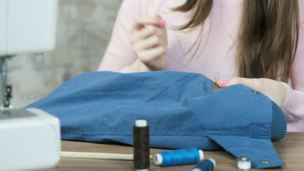 Close-up of the womans hands sewed to the sleeve of the jacket leather brown insert. Front view. — Stock Video