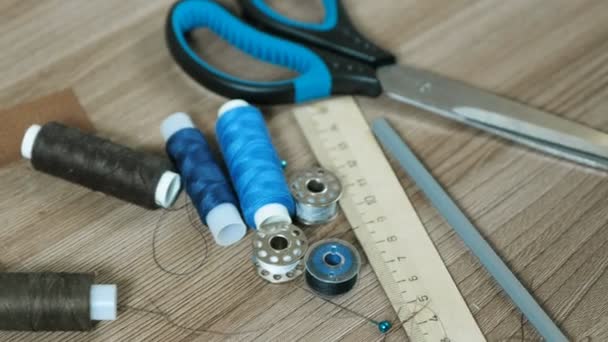 La costura abastece las tijeras, el hilo, las bobinas, el lápiz, la regla a la mesa de madera. Vista lateral . — Vídeos de Stock