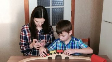 Birlikte oynayan. Anne telefon görünüyor ve son tren, vagonlar ve masada oturan tünel ile ahşap bir demiryolu çalacak.